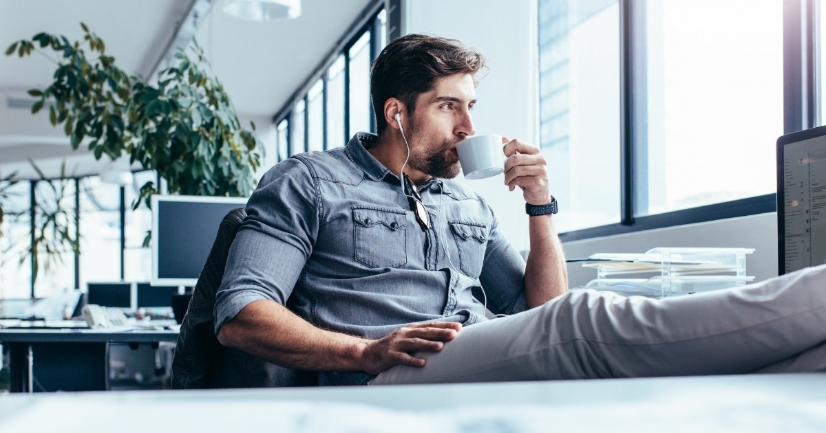 A man sips coffee at his desk