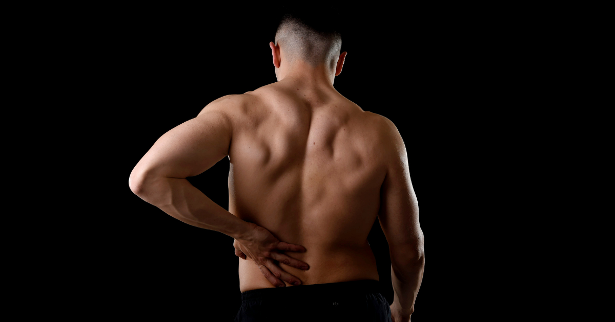 A man holds his lower back after a weightlifting injury