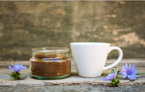 Espresso cup next to a jar of ground coffee beans